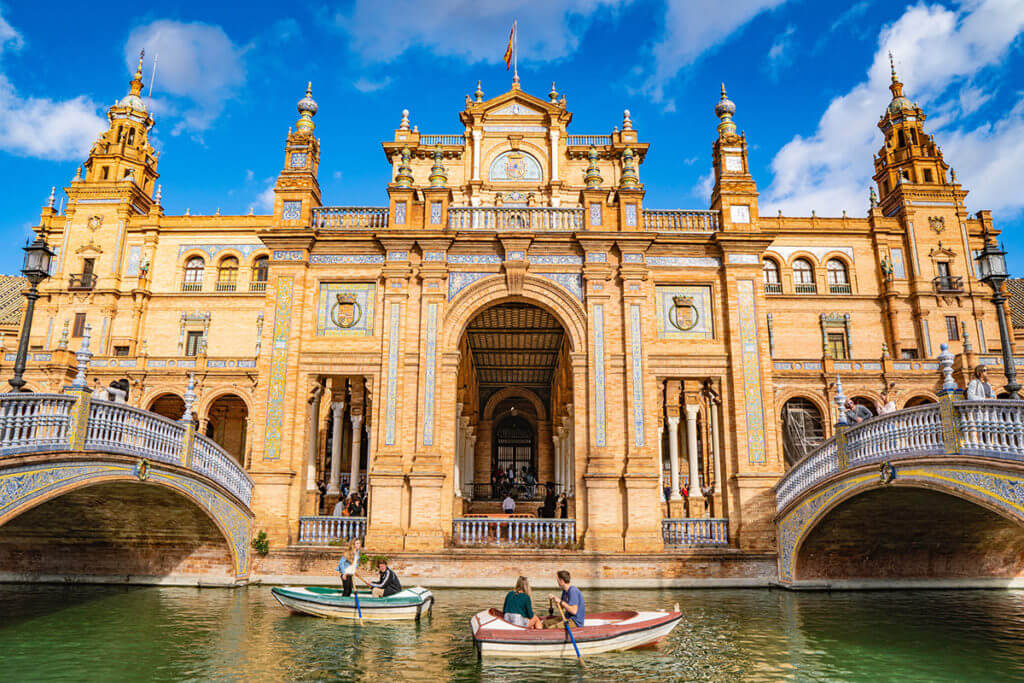 A central image of La Plaza De Espana with people rowing boats along the canal in front